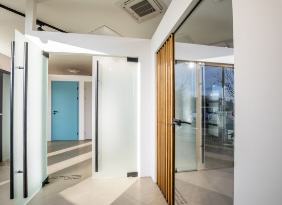 Kliknutím zvětšíte Detail skleněných dveří SAPELI z bezpečnostního vrstveného skla a se speciálním kováním, showroom PRO-K v Českých Budějovicích.