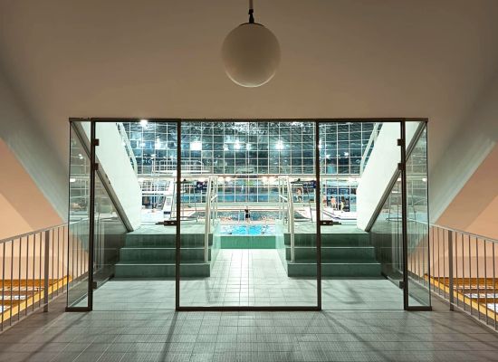 Skleněná stěna z bezpečnostního skla v kombinaci s kovovým rámem v rekonstruované plovárně 