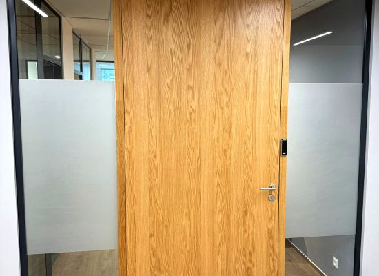 Detail skleněné akustické příčky, která kombinuje bezpečnostní kalené sklo FLOAT 8 mm s leštěnými hranami a dveře s designem přírodního dřeva. Zakázková výroba PRO-K 